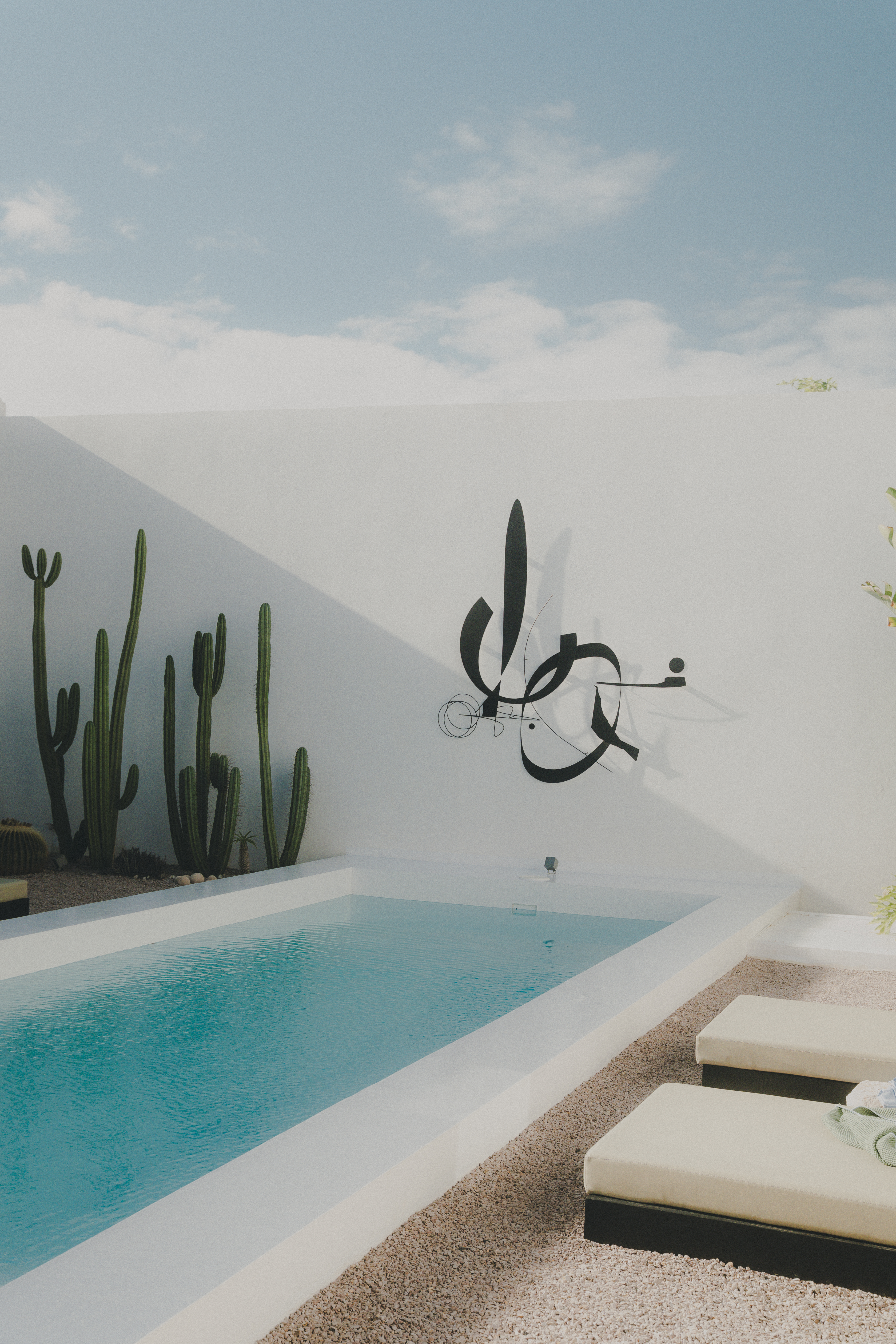 Vista general del patio con piscina y obra artística en Casa Montelongo en La Oliva, Fuerteventura