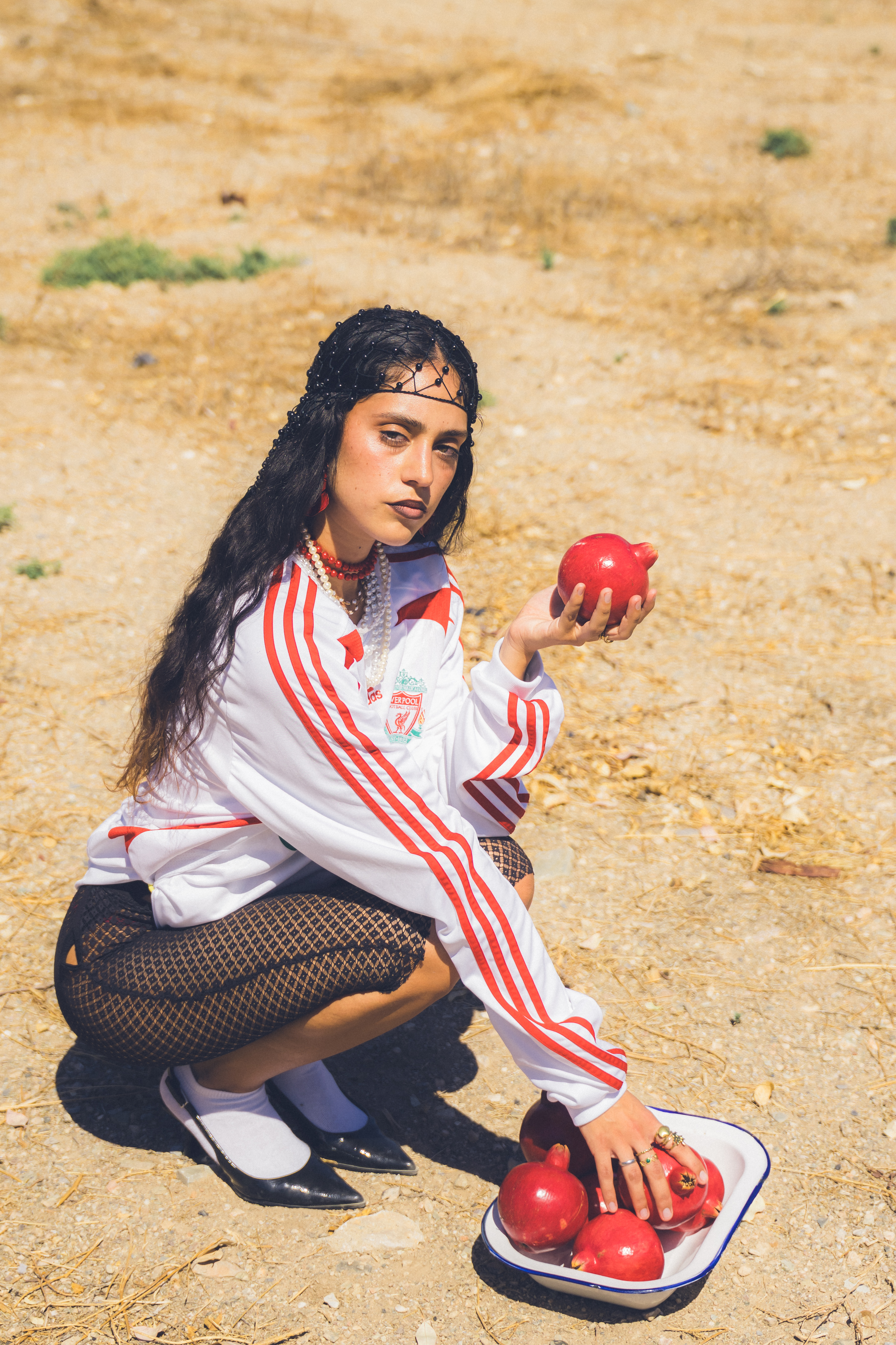 Modelo en un entorno rural sosteniendo un cuenco con frutos rojos en una actitud relajada.