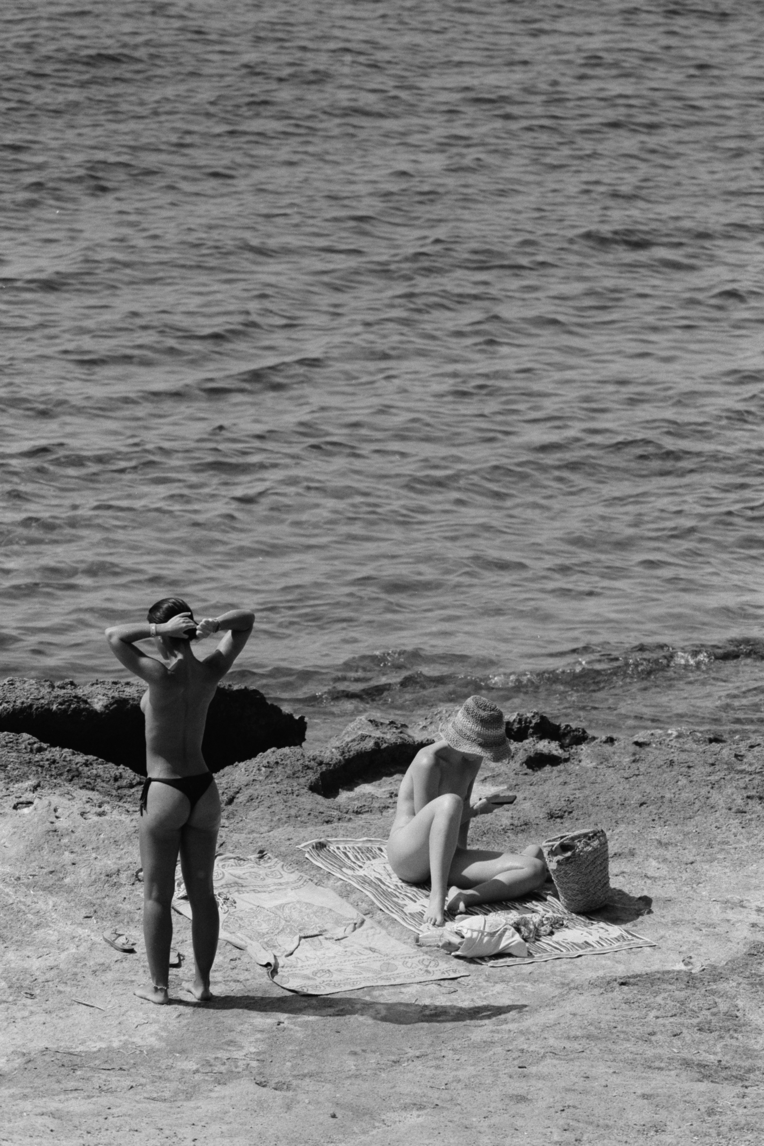 Bañistas descansando en la playa de Alicante bajo la luz del atardecer en blanco y negro