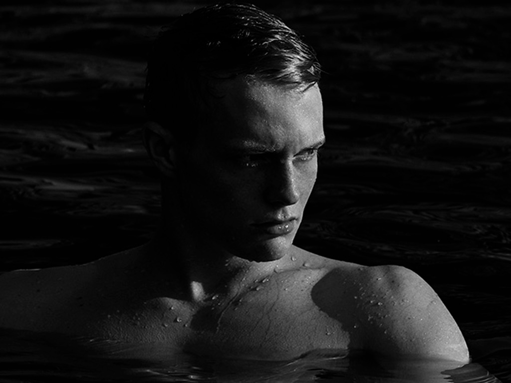 Imagen editorial en blanco y negro de una figura inmersa en el agua