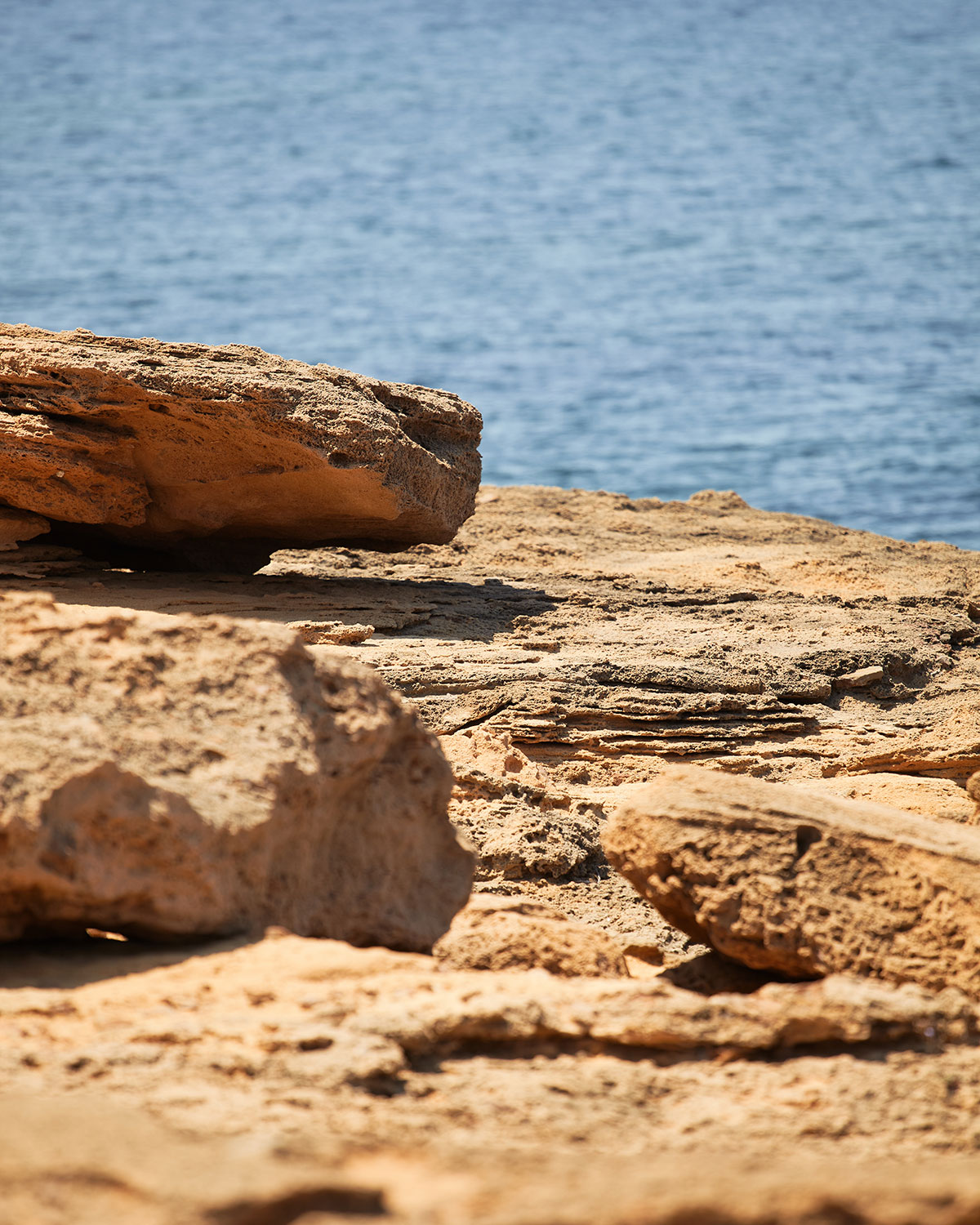 Vista de Cala Pregonda con arena dorada, rocas rojizas y mar azul en la costa norte de Menorca