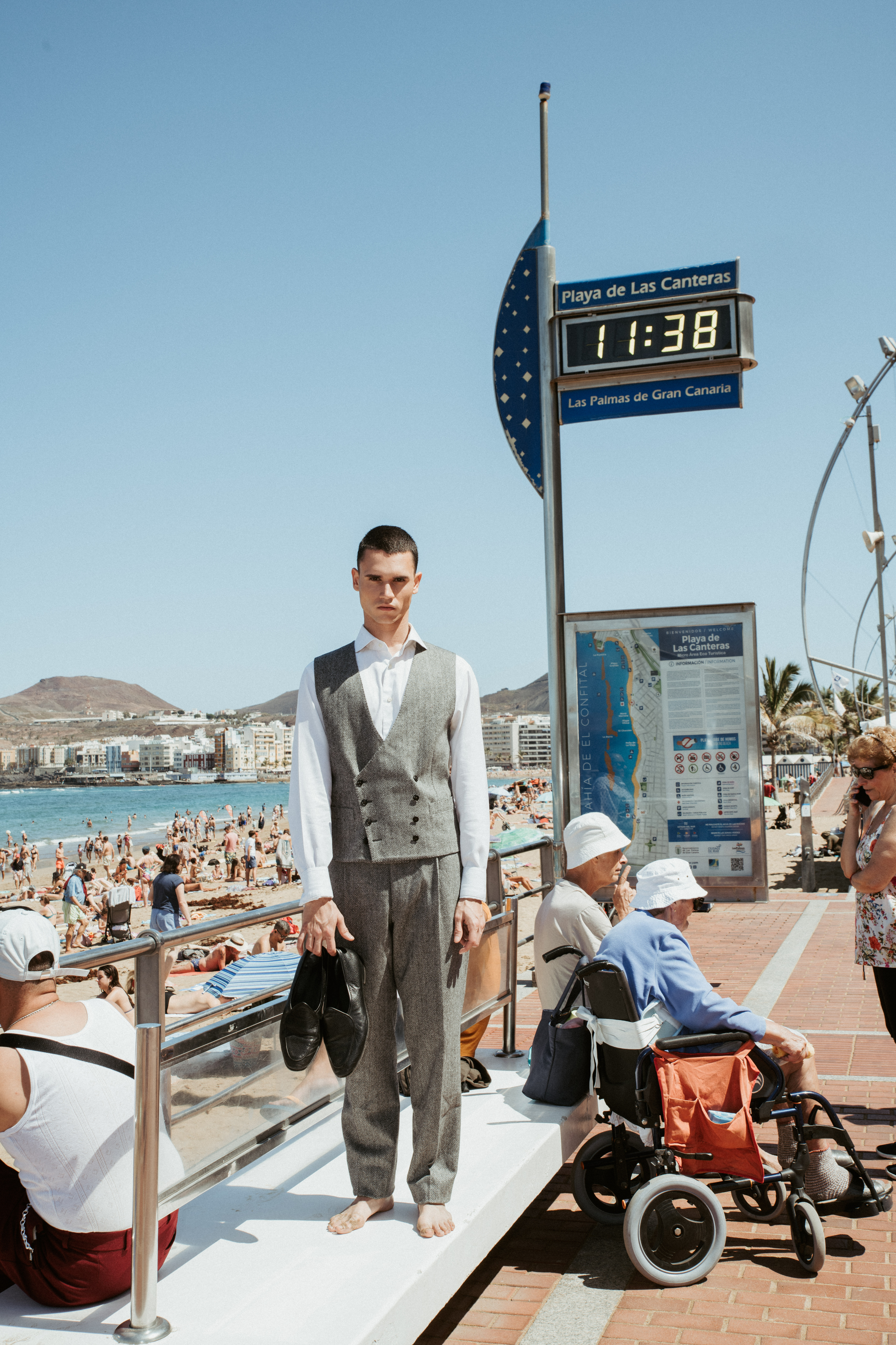 Modelo posando entre turistas durante un editorial de moda ambientado en el verano canario