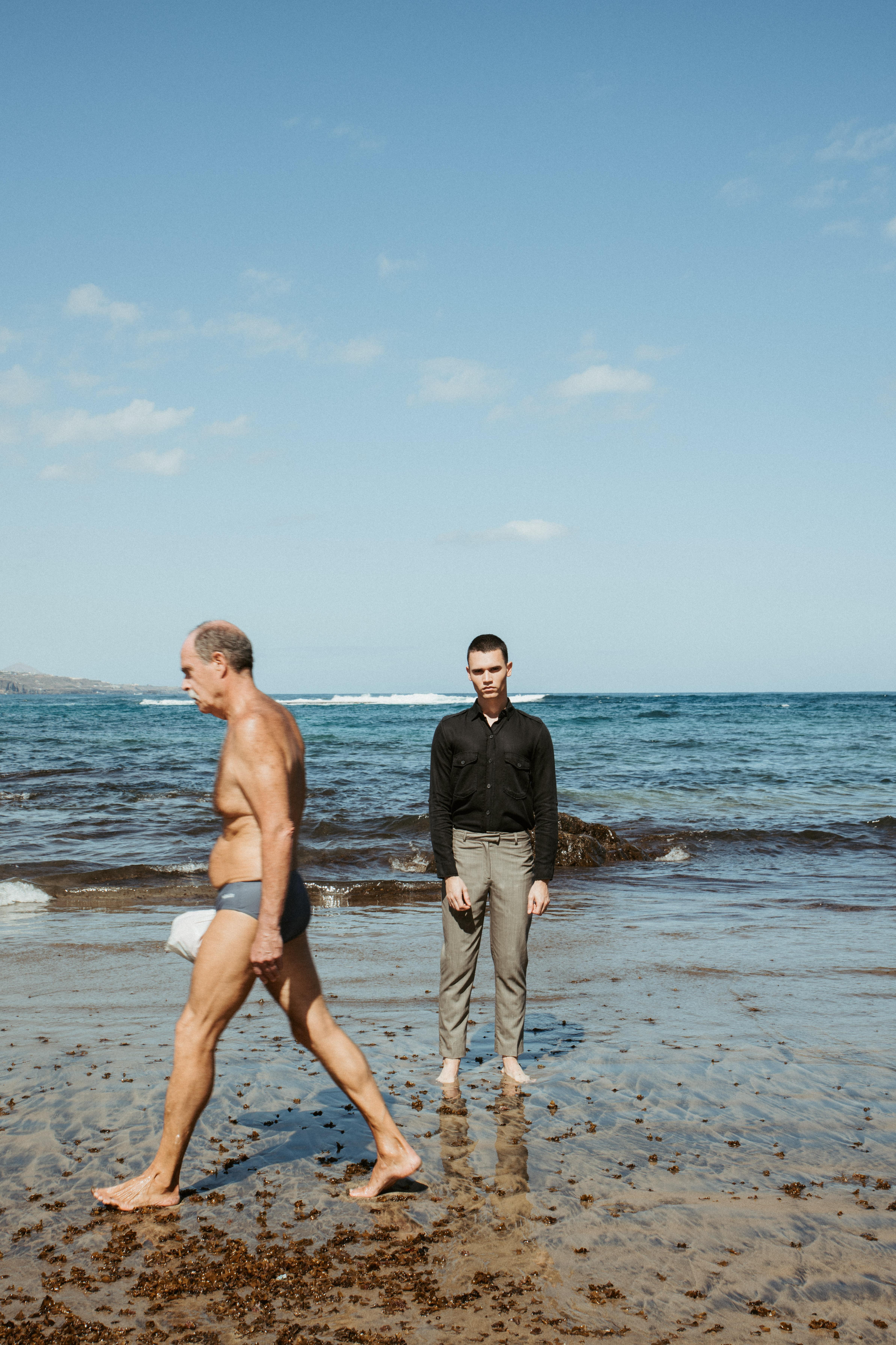 Modelo con traje de sastrería en entorno de playa en editorial de moda
