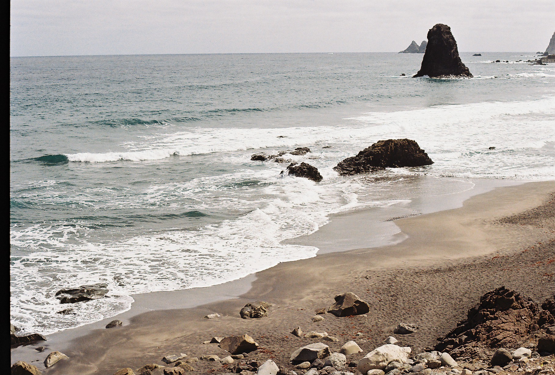 Playa de arena oscura en Tenerife con el océano Atlántico en calma
