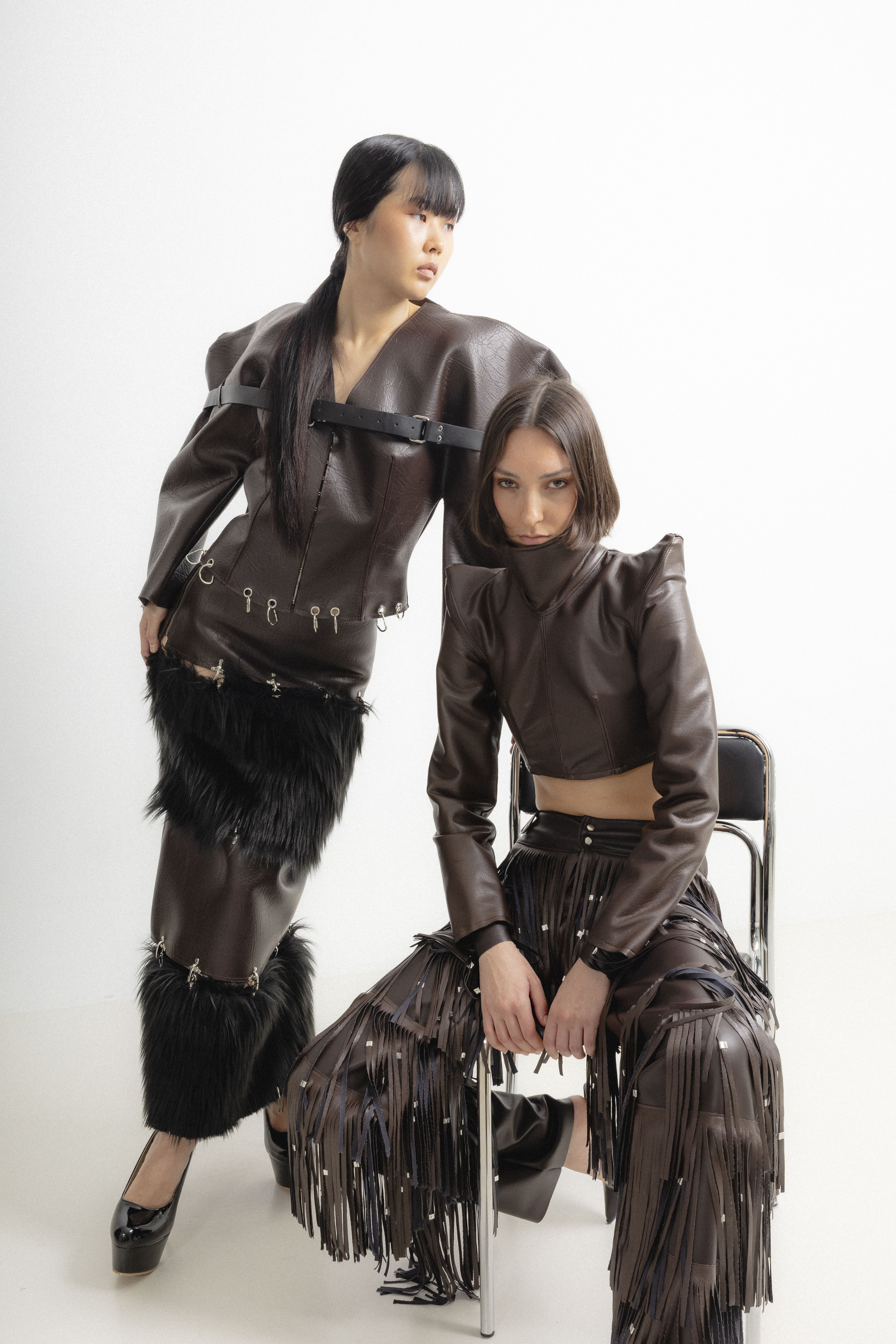 Modelos con prendas de volúmenes escultóricos en polipiel marrón, cinturones, hebillas y detalles metálicos de inspiración ecuestre.