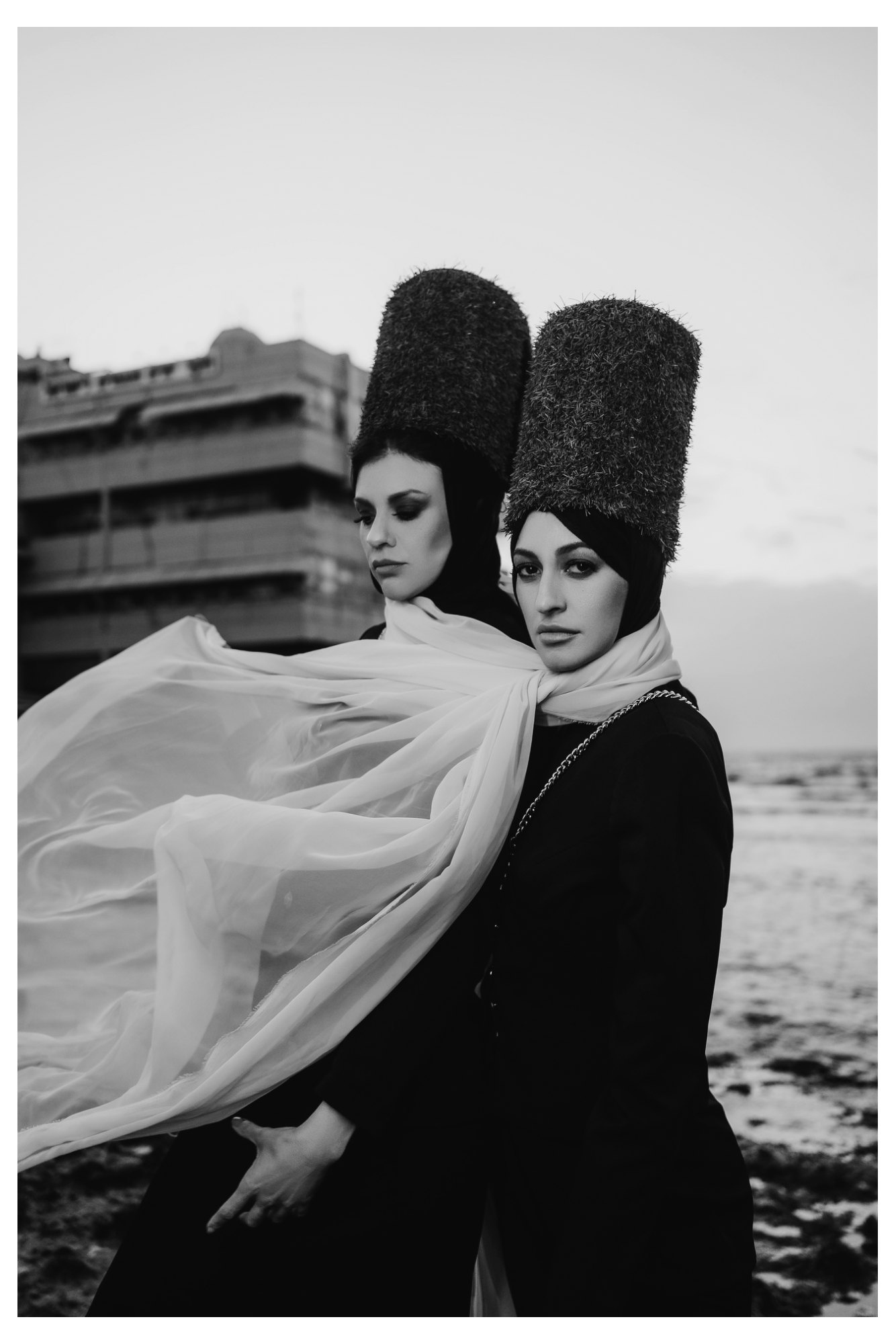 Two women shown in close-up wearing flowing scarves in a black-and-white fashion editorial