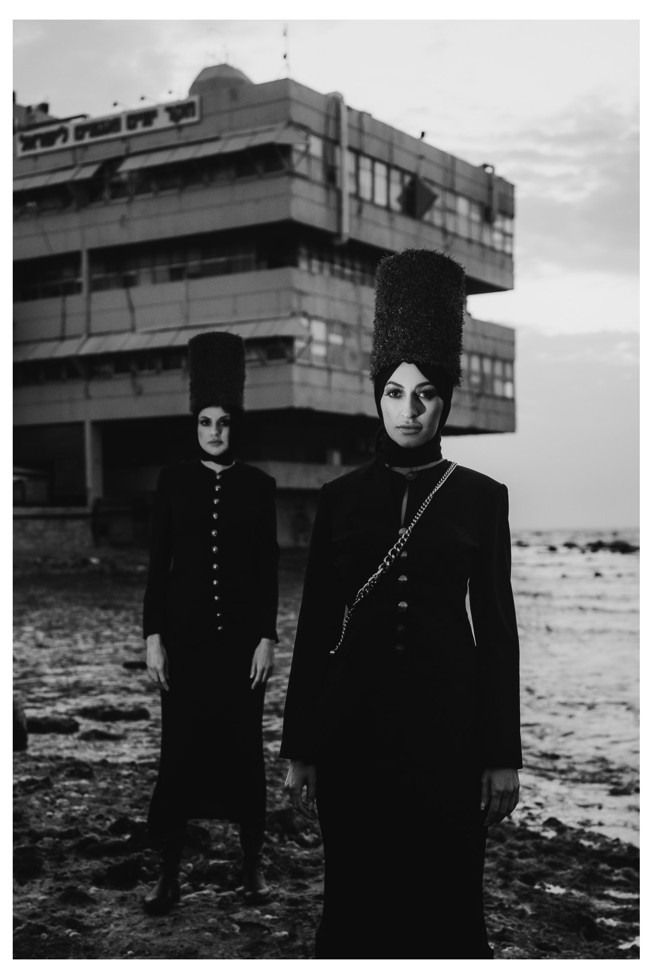 Two women standing one behind the other, wearing dramatic structured crinolines and towering hats in a fashion editorial