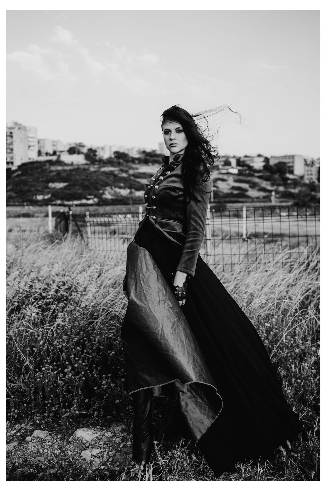 A woman with loose hair in the wind wearing a structured military jacket in a fashion editorial